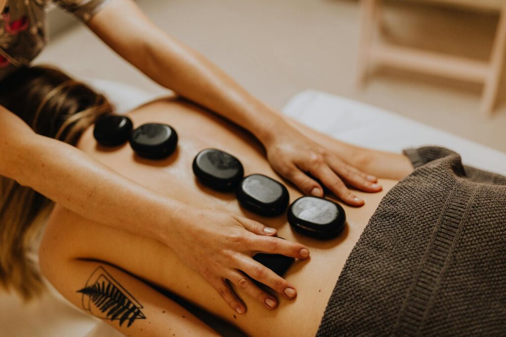 A therapist performing hot stone massage on a client’s back in Vaughan