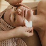 A woman receiving relaxing facial massage therapy in Newmarket at PhysioChiroWellness clinic.