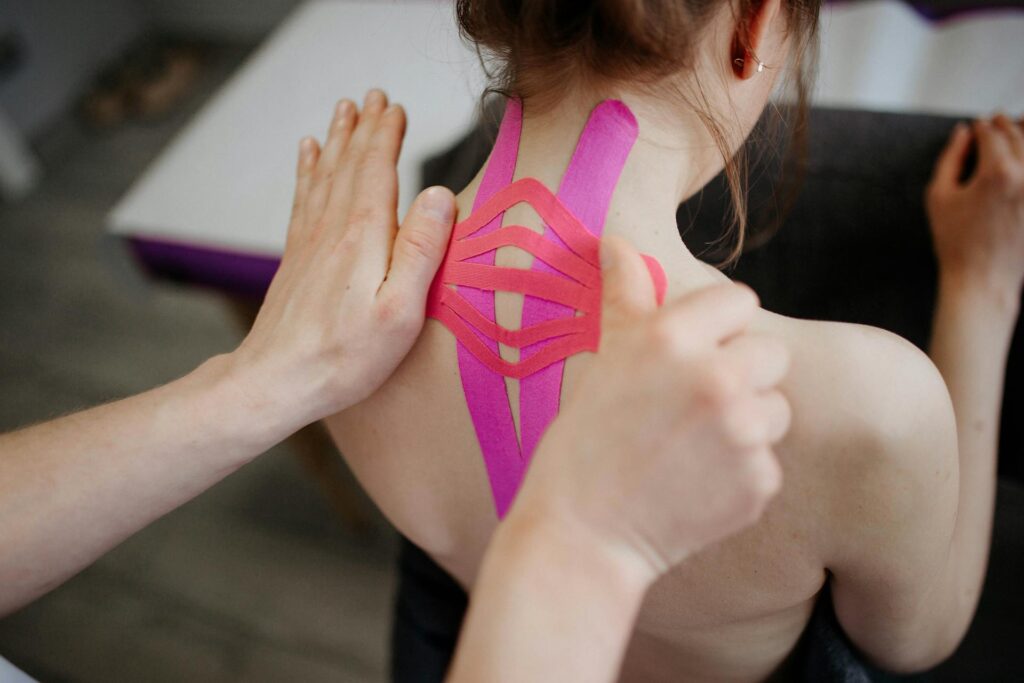 Chiropractor in Newmarket applying Kinesio tape to patient's shoulder for pain relief and stability