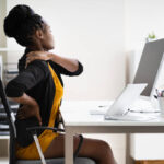 Professional chiropractor in Newmarket adjusting a patient's posture at an ergonomic workstation