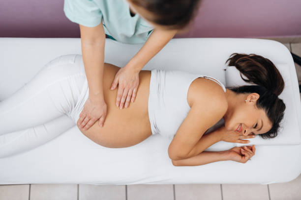 A pregnant woman receiving a gentle side-lying massage from a therapist in Newmarket
