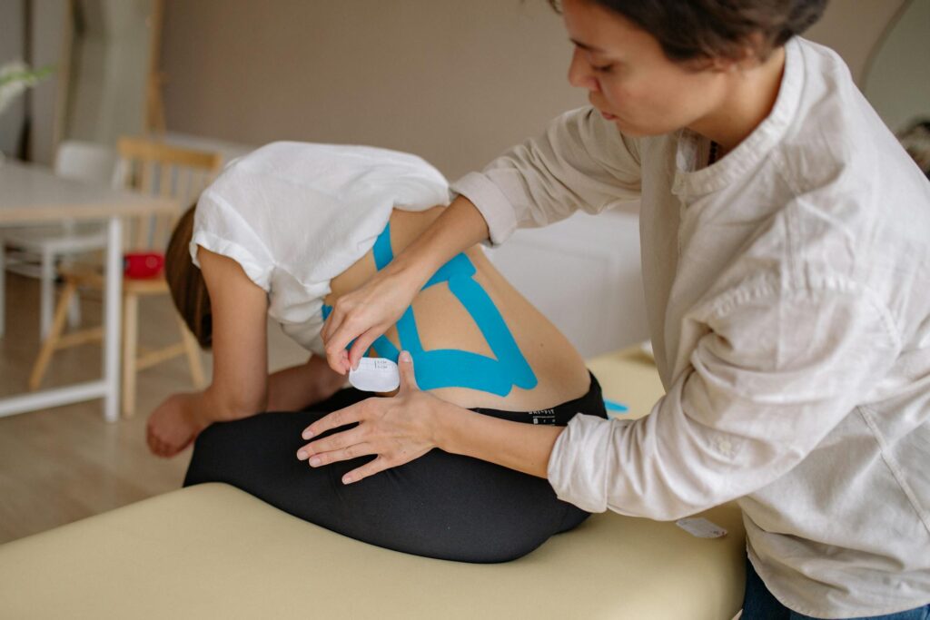 Physiotherapist applying kinesiology tape to a patient’s knee during a physiotherapy session in Newmarket
