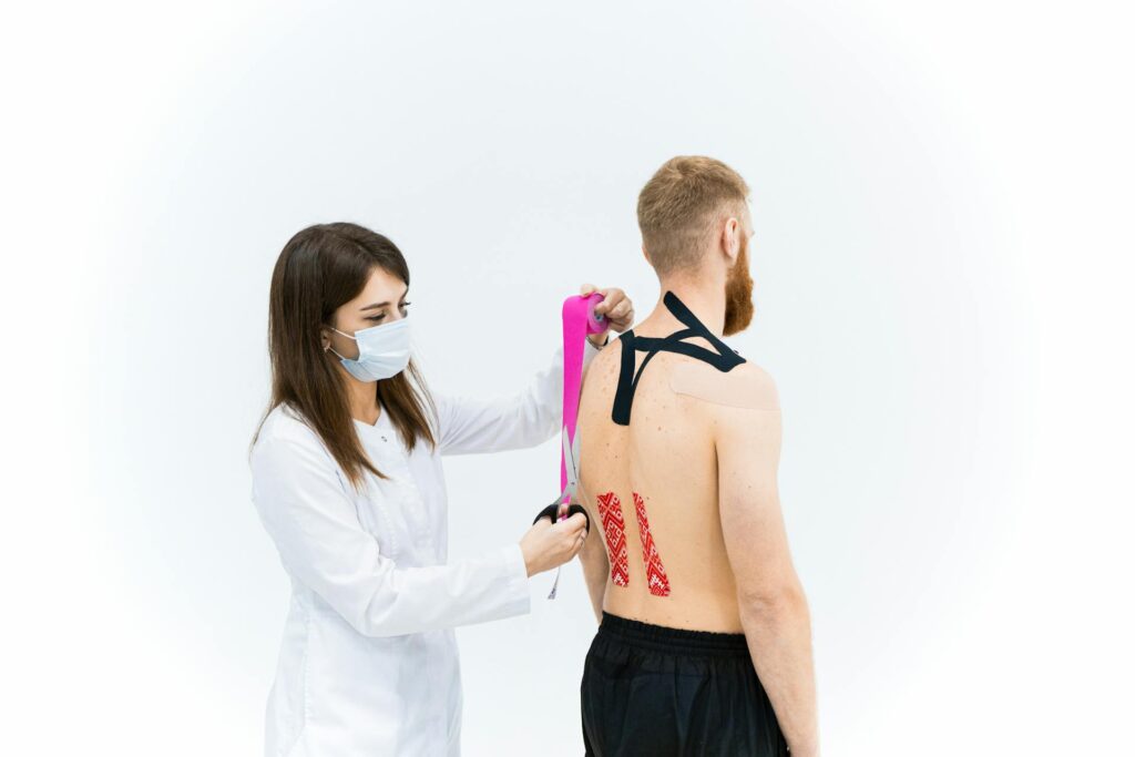 Physiotherapist in Vaughan applying Kinesio tape to a patient's shoulder at PhysioChiroWellness clinic
