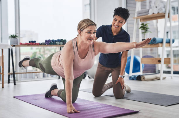 A Newmarket physiotherapist guides a patient through corrective exercises alongside yoga and Pilates mats. A Newmarket physiotherapist guides a patient through corrective exercises alongside yoga and Pilates mats.