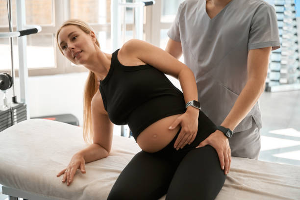A pregnant woman lying on a chiropractic table receiving gentle back adjustment from a female chiropractor in Vaughan clinic